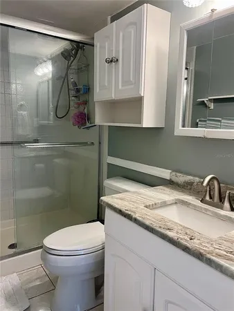 a bathroom with a granite countertop sink mirror vanity and toilet
