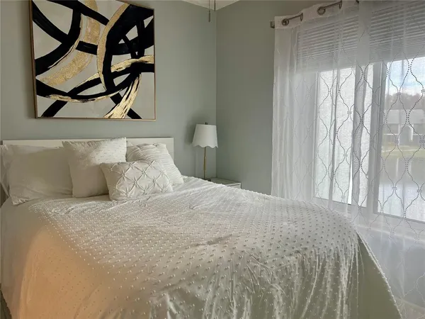 a large white bed in a small room next to a window