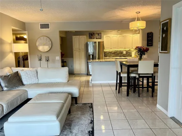 a living room with furniture a dining table and a refrigerator