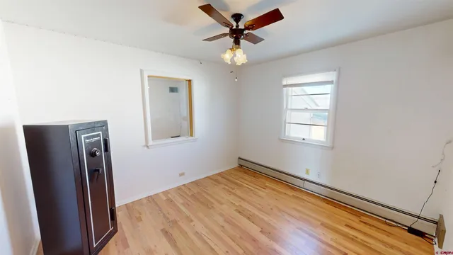 a view of empty room with wooden floor and fan