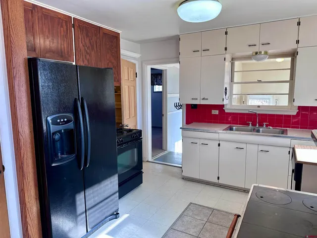 a kitchen with granite countertop a refrigerator sink and cabinets