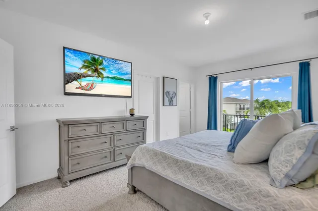 a bedroom with a bed and a flat tv screen on dresser next to a window