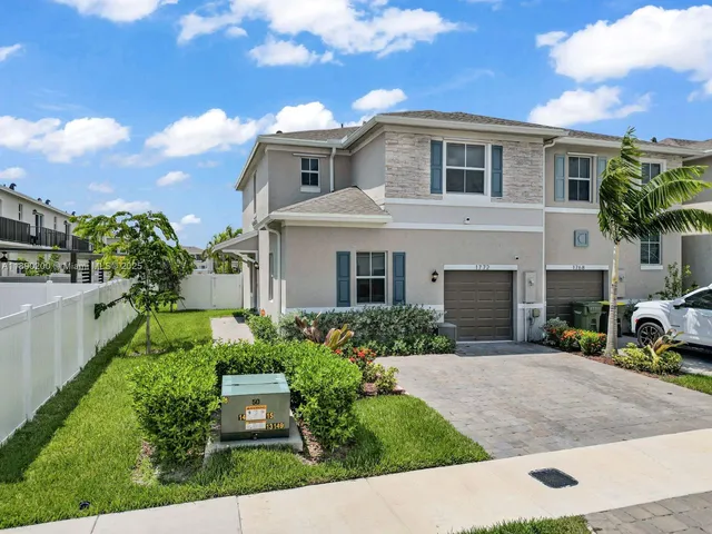 a front view of a house with a yard and potted plants