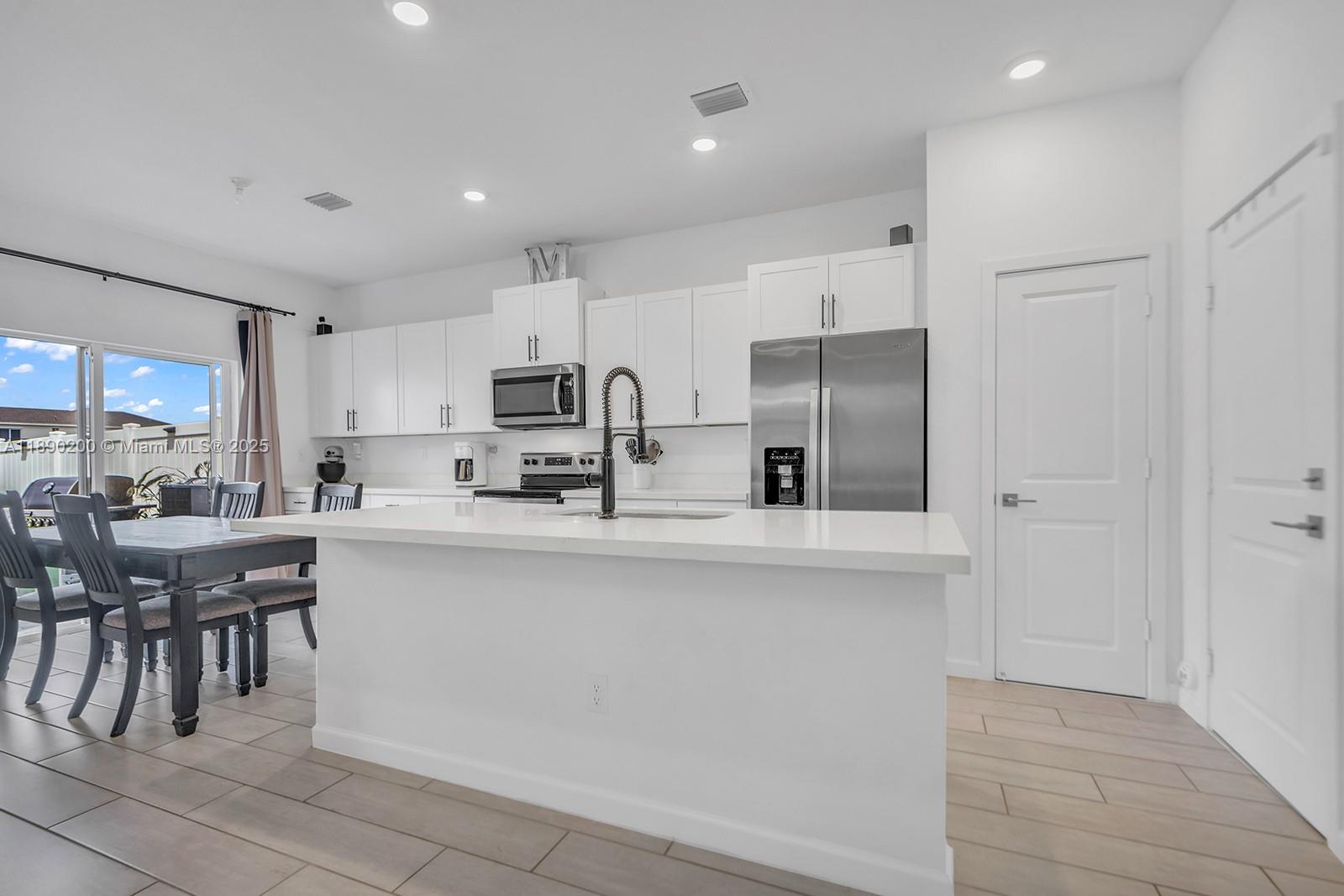 1772 Southeast 8th Street Homestead, FL 33033 - Photo 6 of 42 a kitchen with stainless steel appliances a table and chairs in it