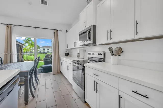 a kitchen with stainless steel appliances white cabinets a sink and a stove