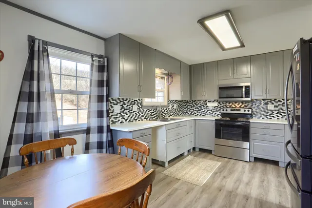 a kitchen with stainless steel appliances a stove a sink dishwasher a microwave oven with a dining table and chairs