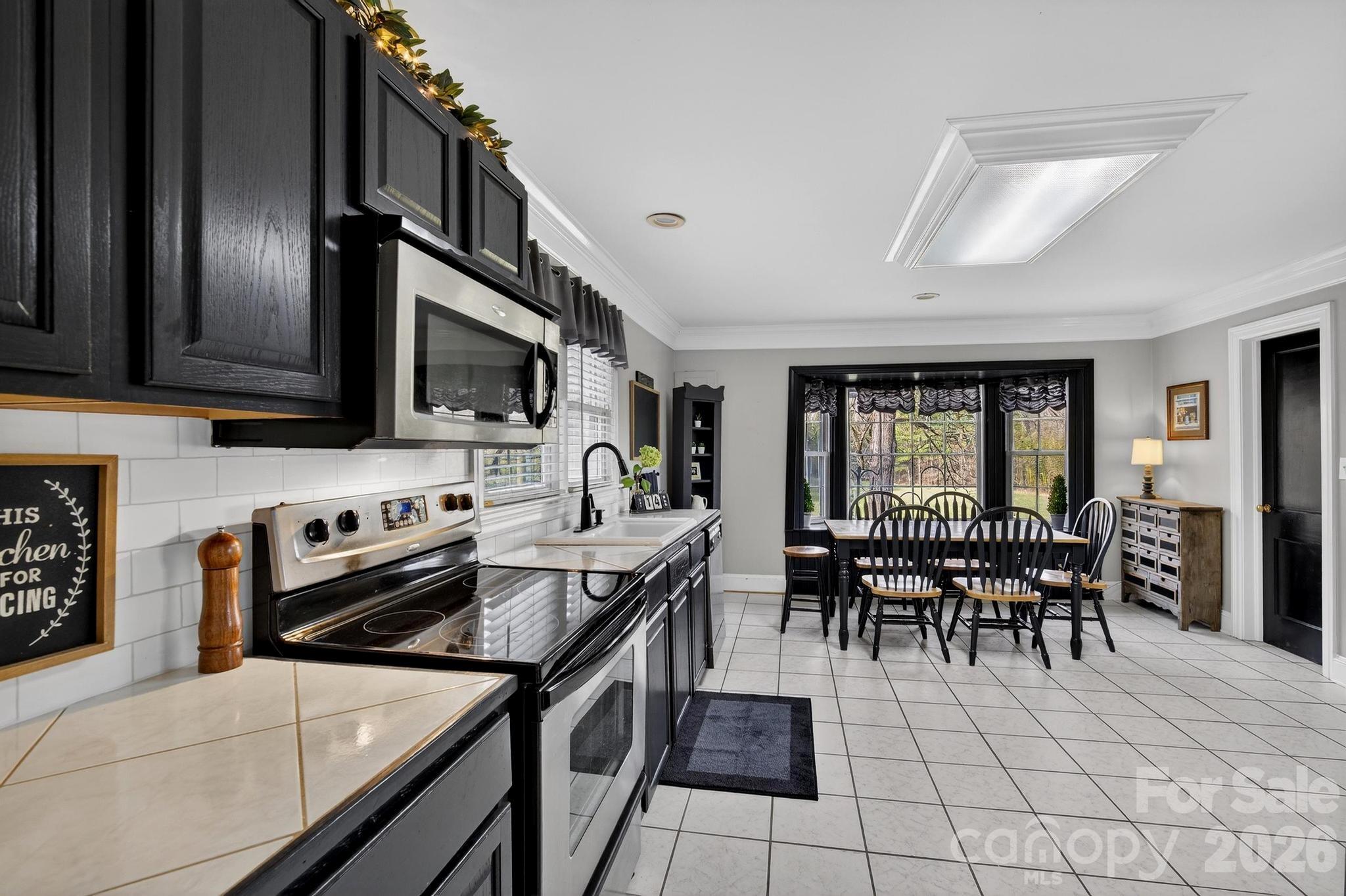 343 Hoyles Creek Road Dallas, NC 28034 - Photo 18 of 31 a kitchen with stainless steel appliances granite countertop a stove top oven a sink a dining table and chairs with wooden floor
