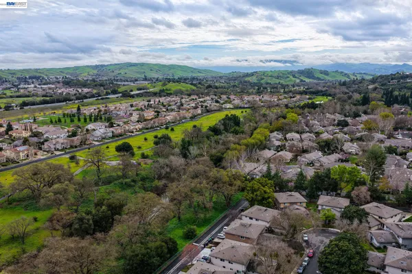 an aerial view of a residential houses with outdoor space and trees