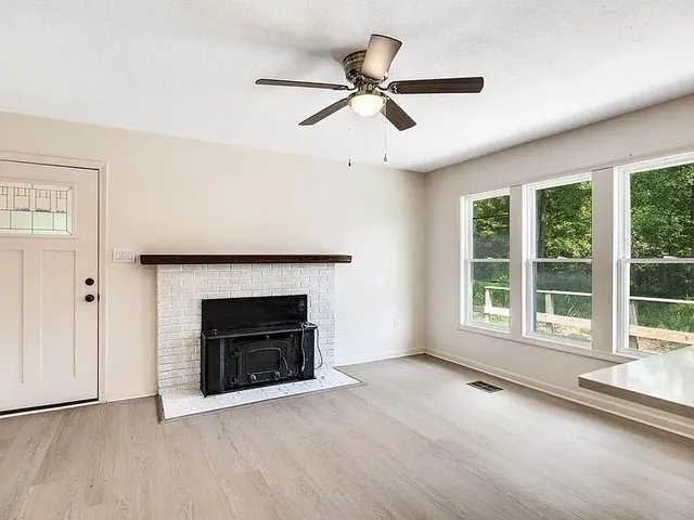 an empty room with windows and fireplace