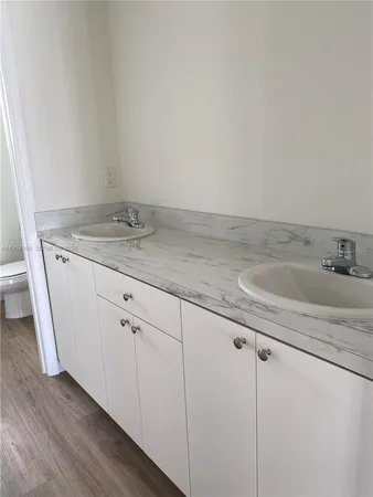 a bathroom with a granite countertop sink and white cabinets