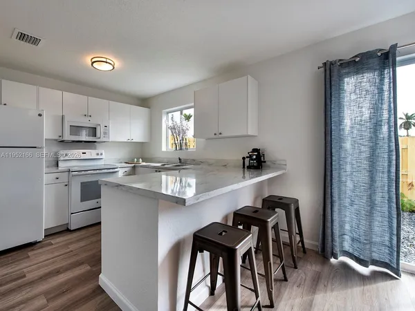 a kitchen with a table chairs a sink dishwasher window and cabinets
