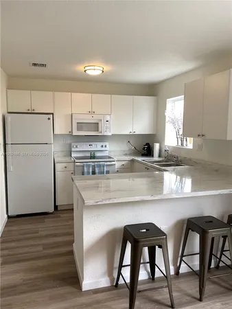 a kitchen with cabinets wooden floor and stainless steel appliances