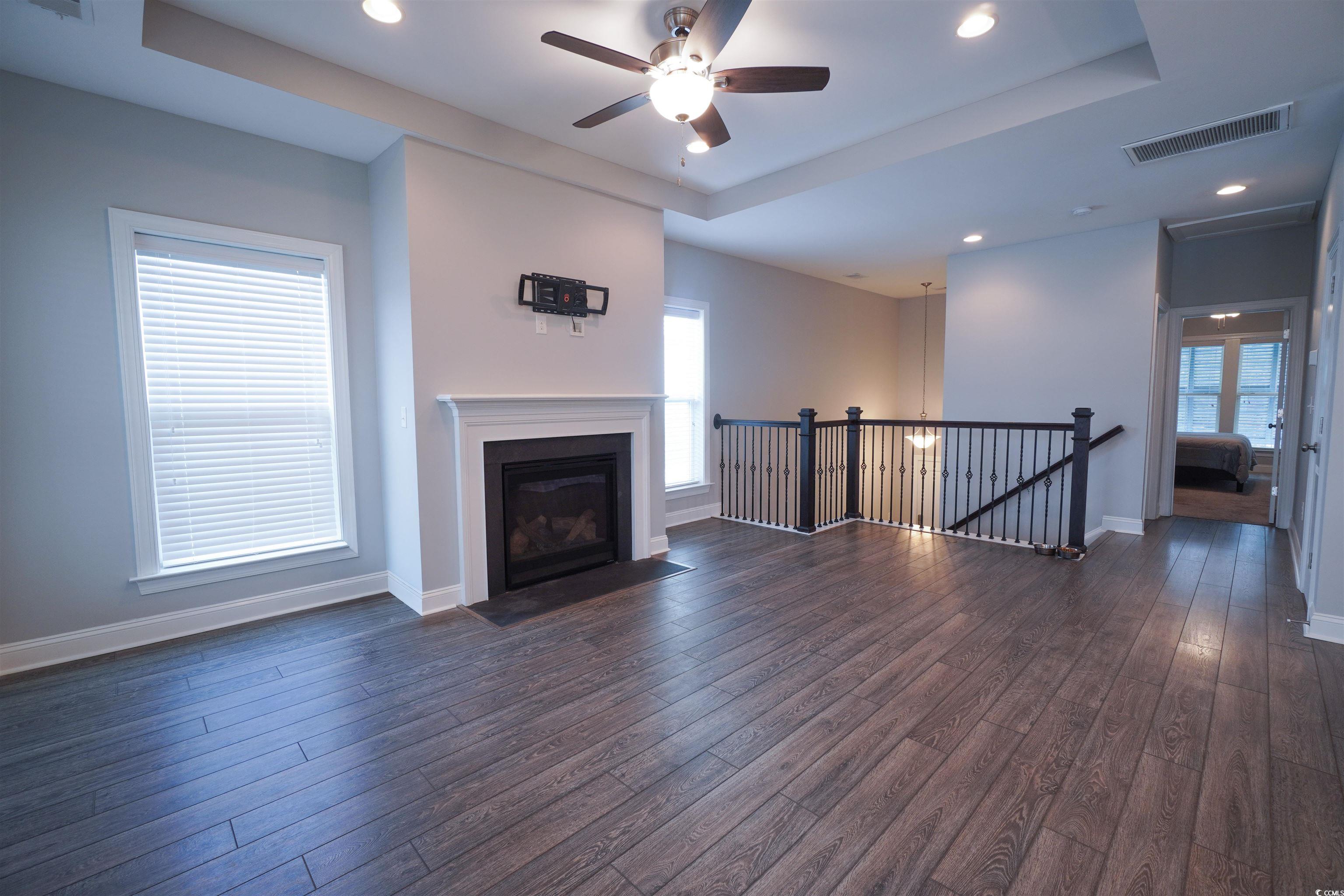 100 Splendor Circle Murrells Inlet, SC 29576 - Photo 23 of 40 Living room ,recessed lighting, dark wood-style flooring, a fireplace with flush hearth, Tray ceiling, and a ceiling fan