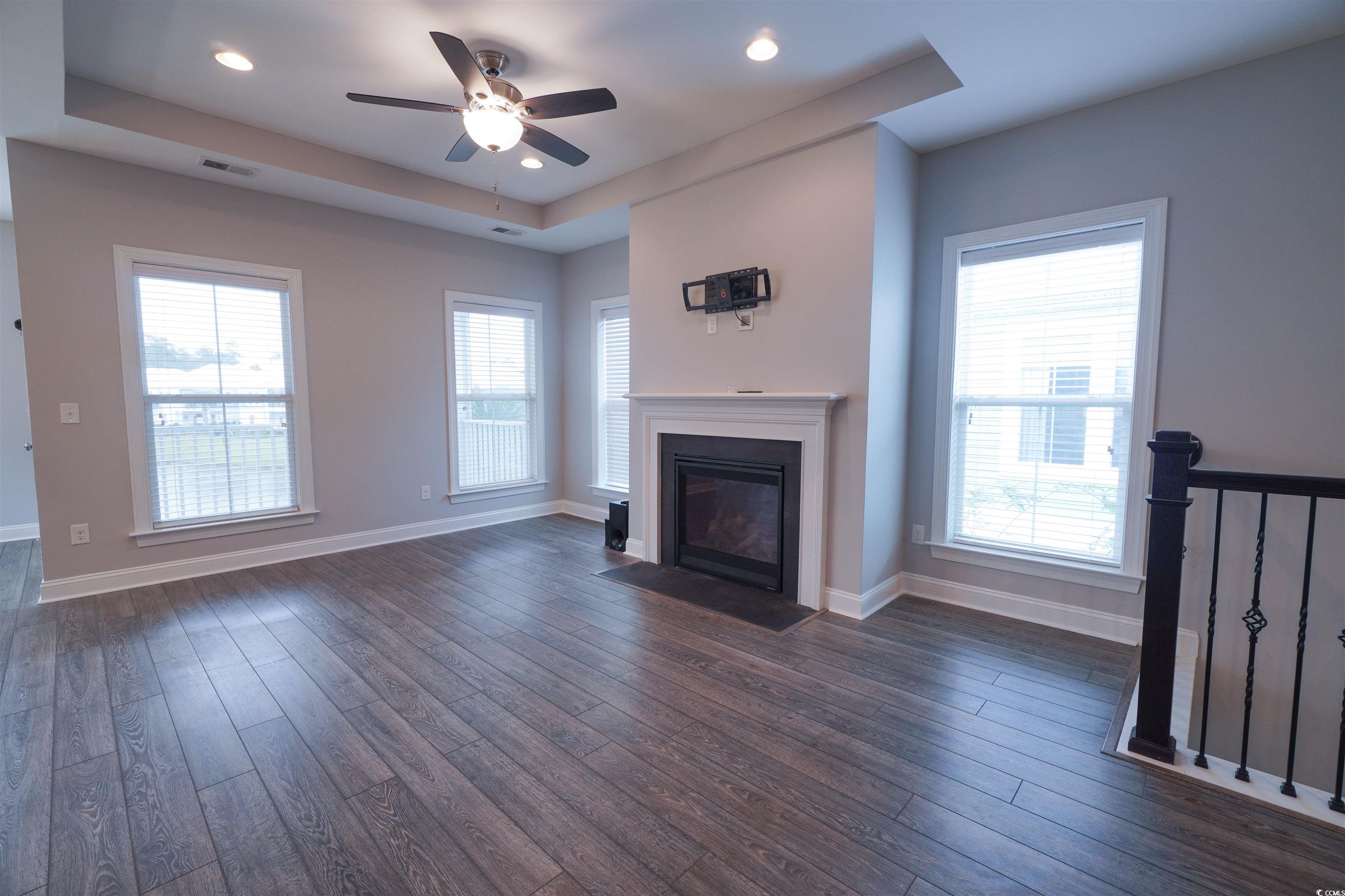 100 Splendor Circle Murrells Inlet, SC 29576 - Photo 24 of 40 Living room with ceiling fan, a fireplace with flush hearth, dark wood-style flooring, recessed lighting, and a tray ceiling