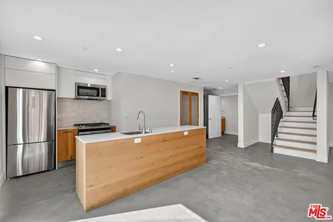 a kitchen with stainless steel appliances granite countertop a refrigerator a stove a sink and a refrigerator