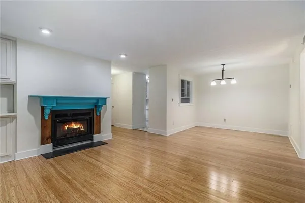 a view of an empty room with wooden floor fireplace and a window