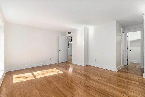 an empty room with wooden floor and windows
