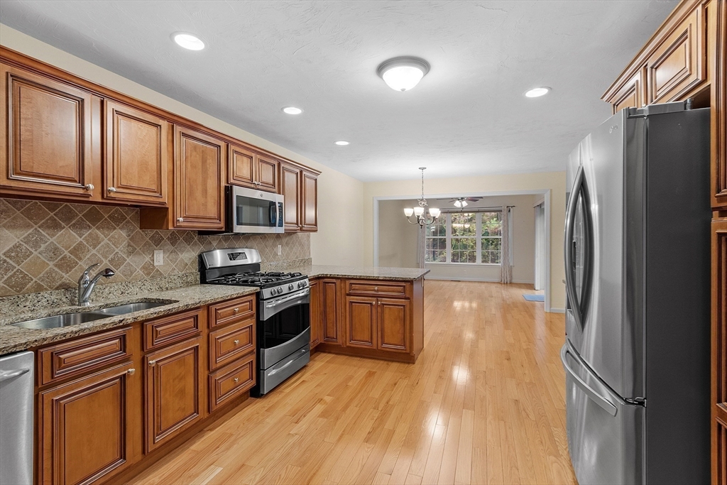 2 Riley Road, Unit C Lunenburg, MA 01462 - Photo 22 of 42 a kitchen with stainless steel appliances granite countertop a refrigerator a stove top oven a sink dishwasher and wooden cabinets with wooden floor