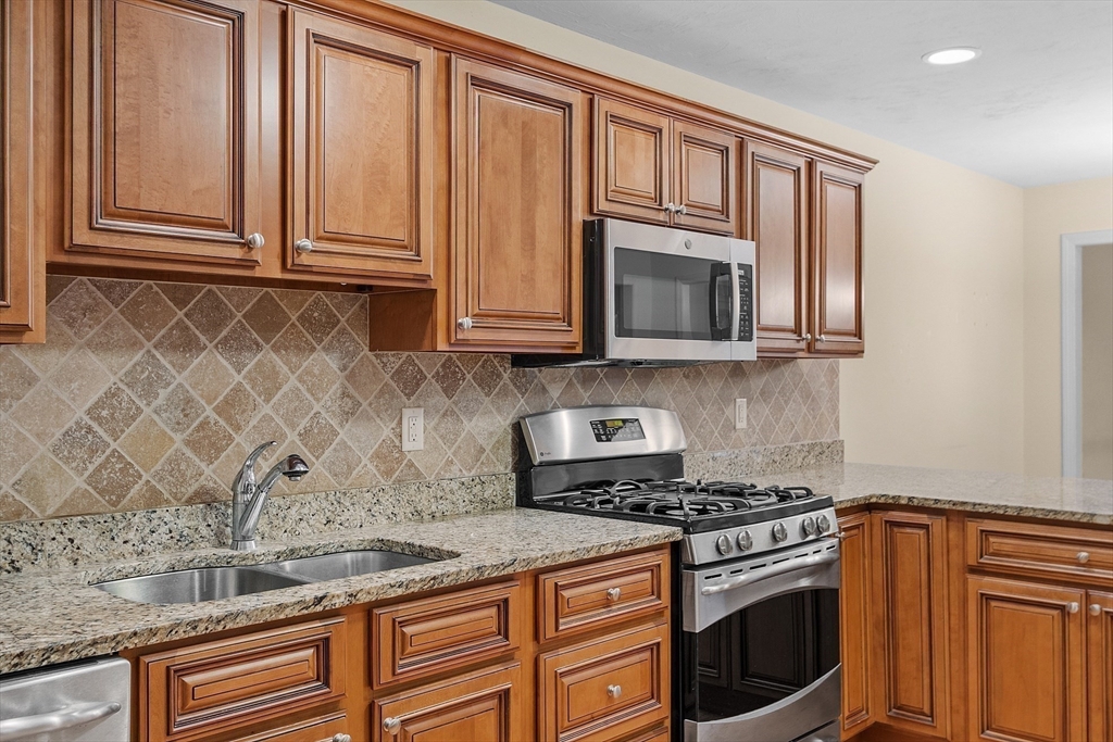 2 Riley Road, Unit C Lunenburg, MA 01462 - Photo 24 of 42 a kitchen with granite countertop cabinets stainless steel appliances and wooden cabinets