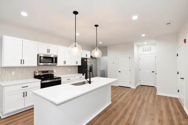 a kitchen with stainless steel appliances a refrigerator sink and white cabinets
