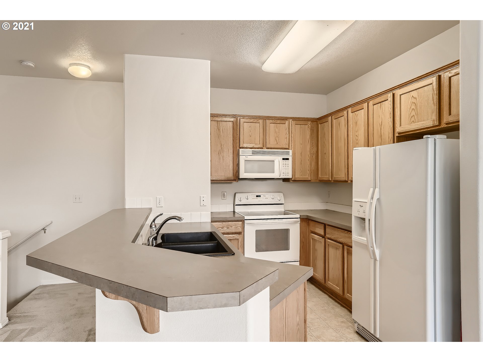 7152 Southwest Manor Way, Unit F Aloha, OR 97078 - Photo 22 of 28 a kitchen with a refrigerator a stove a sink and a dining table