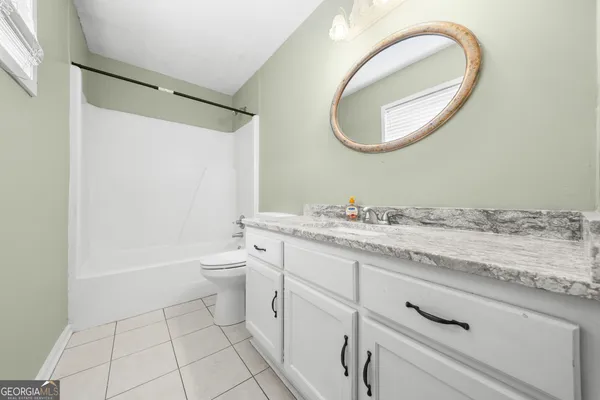 a bathroom with a granite countertop toilet a sink and a mirror