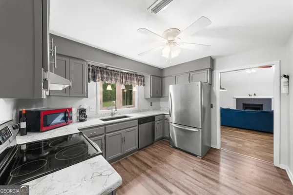 a kitchen with stainless steel appliances a sink cabinets and wooden floor