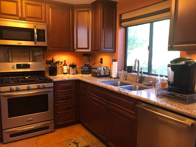 a kitchen with stainless steel appliances granite countertop a stove a sink and a microwave