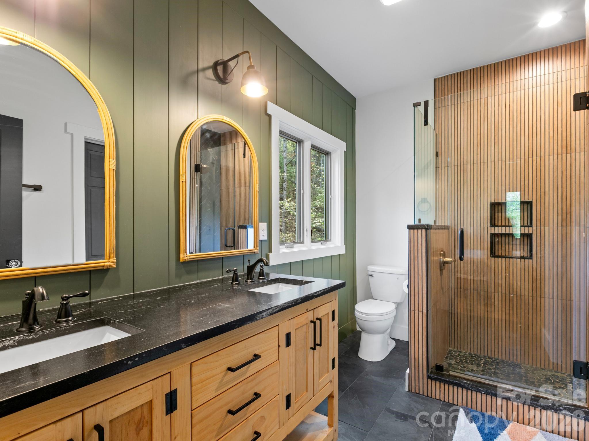 291 Webb Cove Road Asheville, NC 28804 - Photo 18 of 34 a bathroom with double vanity sinks a toilet a mirror and shower