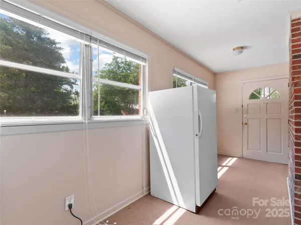 a view of a refrigerator in kitchen and an empty room