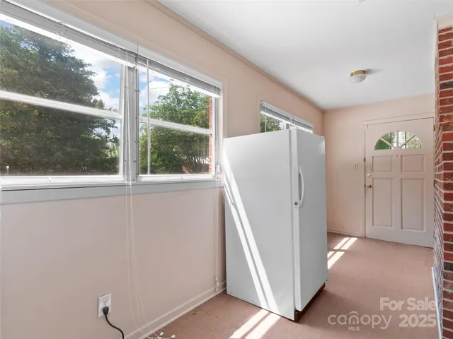 a view of a refrigerator in kitchen and an empty room