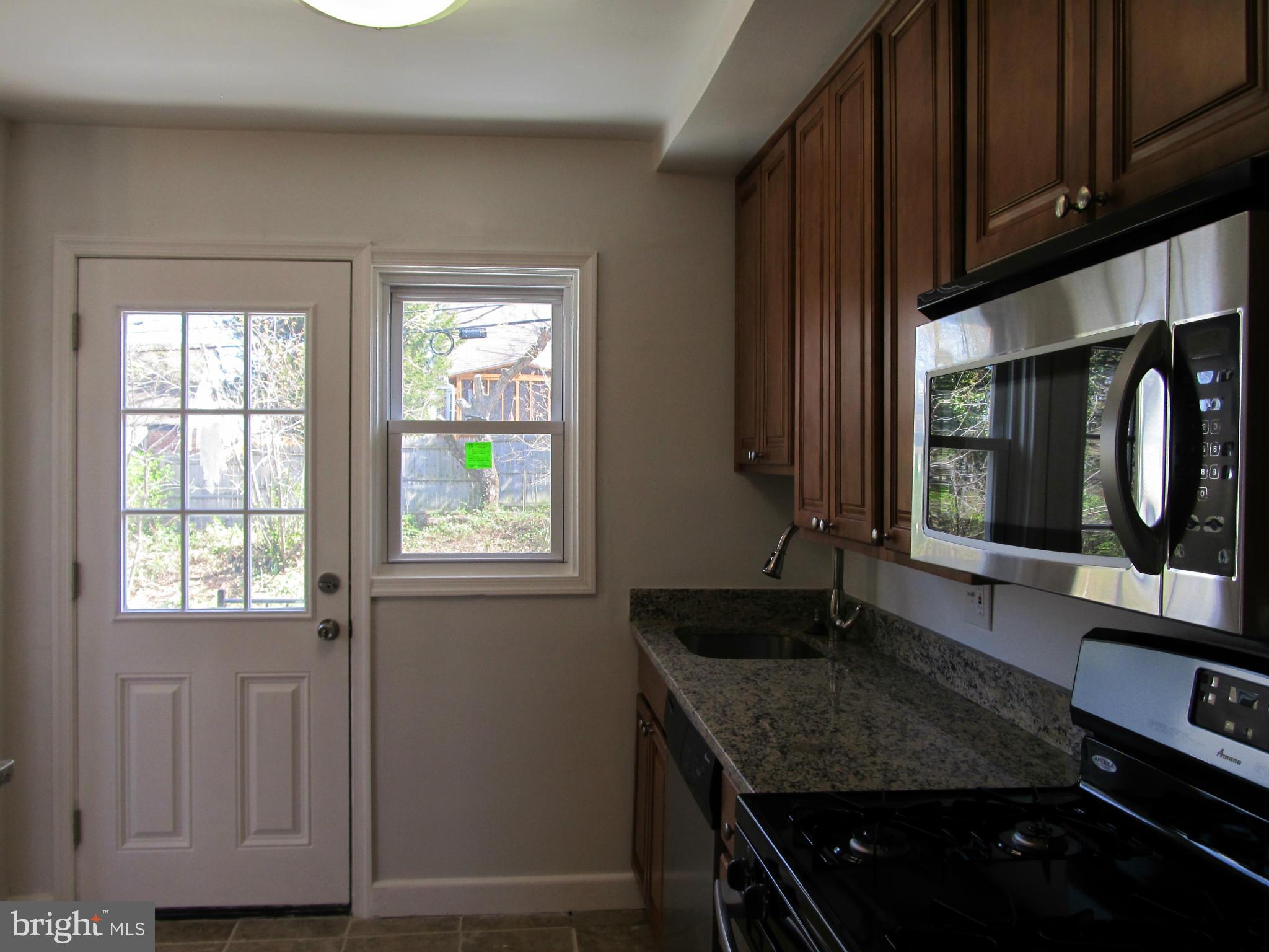 3507 Mayfair Road Baltimore, MD 21207 - Photo 7 of 30 a kitchen with granite countertop wooden cabinets a sink and a window