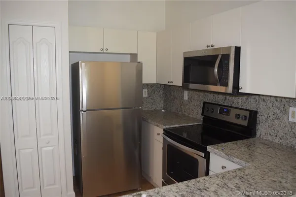 a kitchen with granite countertop cabinets stainless steel appliances and a counter space