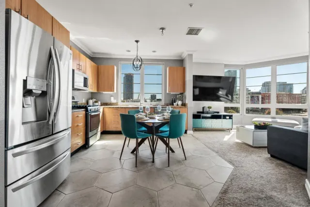 a kitchen with a refrigerator a microwave oven a sink dishwasher and a dining table with wooden floor