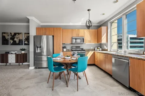 a kitchen with stainless steel appliances granite countertop a sink dishwasher a refrigerator a stove a dining table and chairs with wooden floor