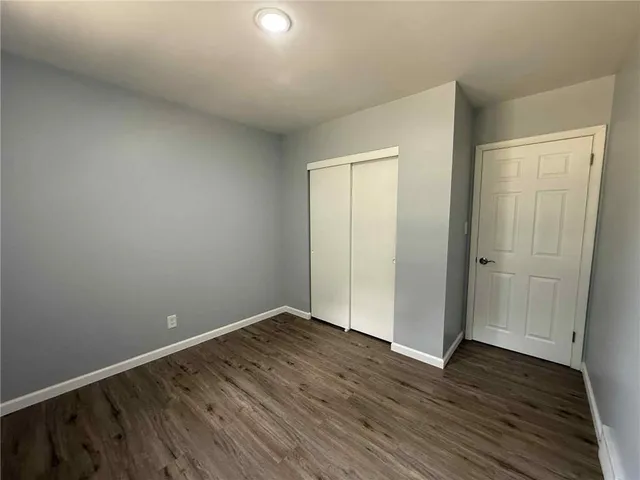 a view of an empty room with wooden floor and closet