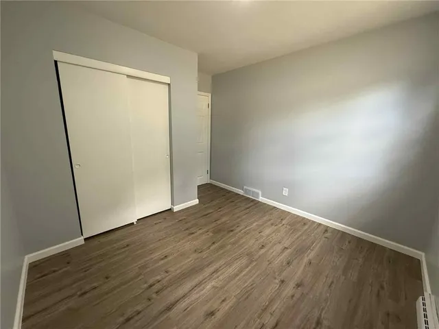 an empty room with wooden floor and closet