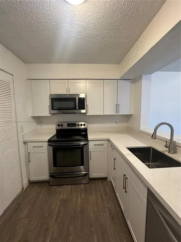 a kitchen with sink a microwave and cabinets