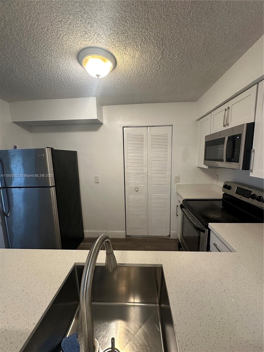 1245 Southwest 46th Avenue, Unit 1202 Pompano Beach, FL 33069 - Photo 3 of 6 a kitchen with a refrigerator and a sink