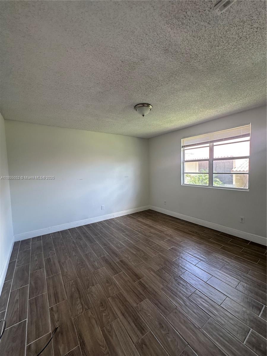 1245 Southwest 46th Avenue, Unit 1202 Pompano Beach, FL 33069 - Photo 4 of 6 an empty room with wooden floor and windows
