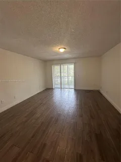 a view of an empty room with wooden floor and glass door