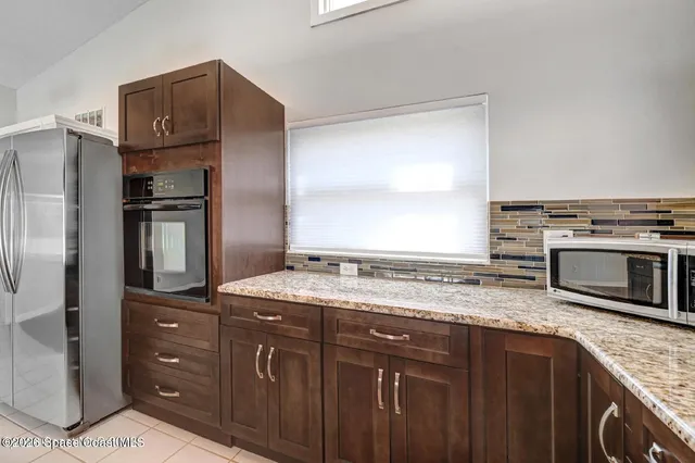 a kitchen with stainless steel appliances granite countertop a refrigerator and a stove top oven