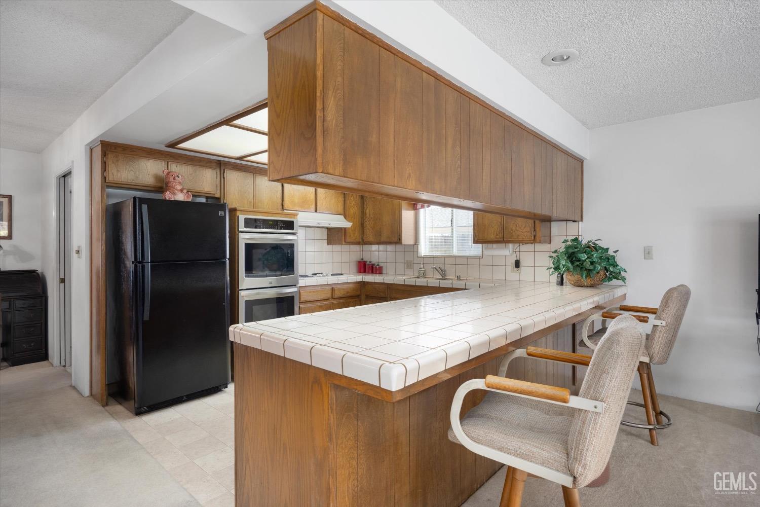 Undisclosed Address Bakersfield, CA 93311 - Photo 16 of 35 a kitchen with a table chairs refrigerator and microwave
