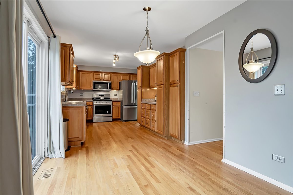 2591 Smithfield Lane Aurora, IL 60503 - Photo 3 of 31 a view of a kitchen with a sink wooden floor stainless steel appliances and cabinets