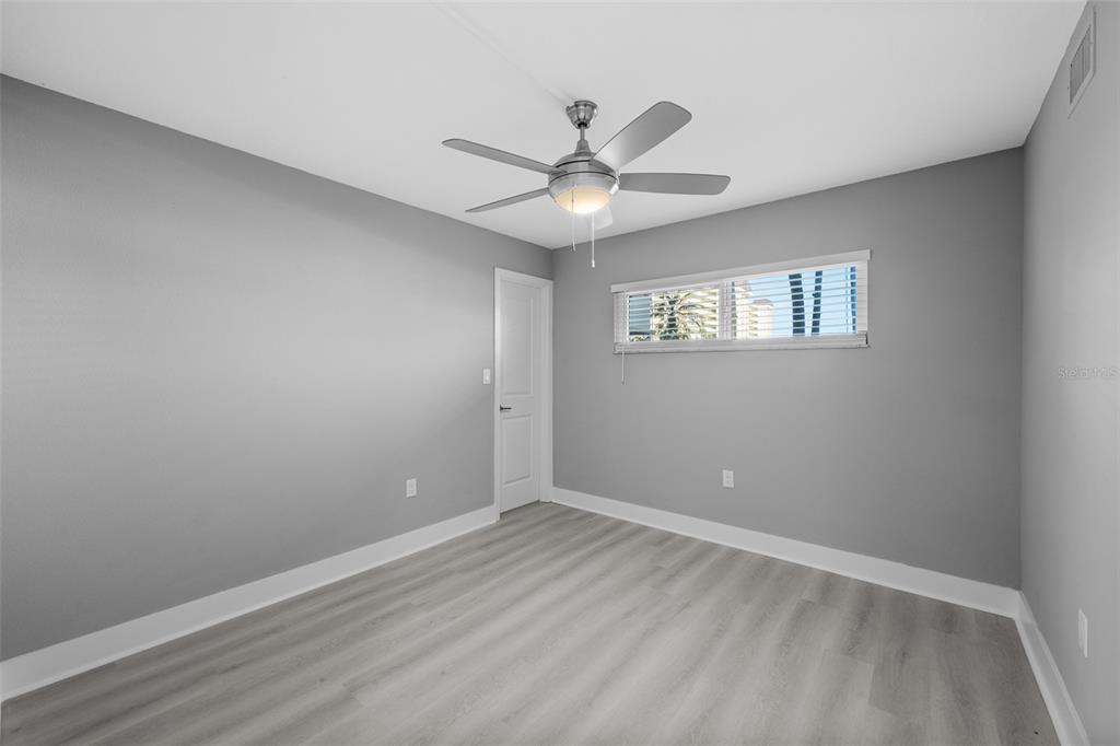4775 Cove Circle, Unit 103 St. Petersburg, FL 33708 - Photo 15 of 61 an empty room with wooden floor ceiling fan and window