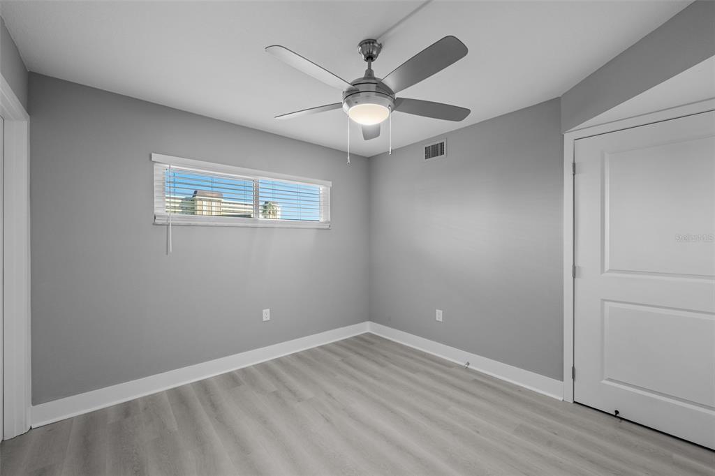 4775 Cove Circle, Unit 103 St. Petersburg, FL 33708 - Photo 18 of 61 an empty room with wooden floor ceiling fan and windows
