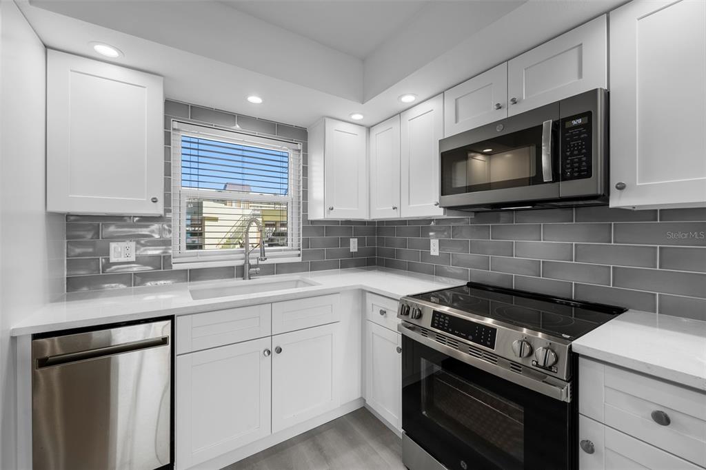 4775 Cove Circle, Unit 103 St. Petersburg, FL 33708 - Photo 4 of 61 a kitchen with white cabinets appliances and a sink