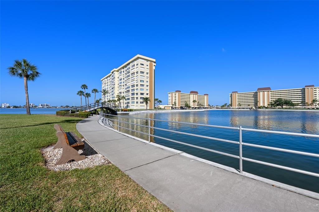 4775 Cove Circle, Unit 103 St. Petersburg, FL 33708 - Photo 56 of 61 a view of a swimming pool with a bench and trees in the background