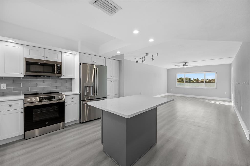 4775 Cove Circle, Unit 103 St. Petersburg, FL 33708 - Photo 8 of 61 a kitchen with stainless steel appliances granite countertop a refrigerator a stove top oven a sink dishwasher and a refrigerator with wooden floor