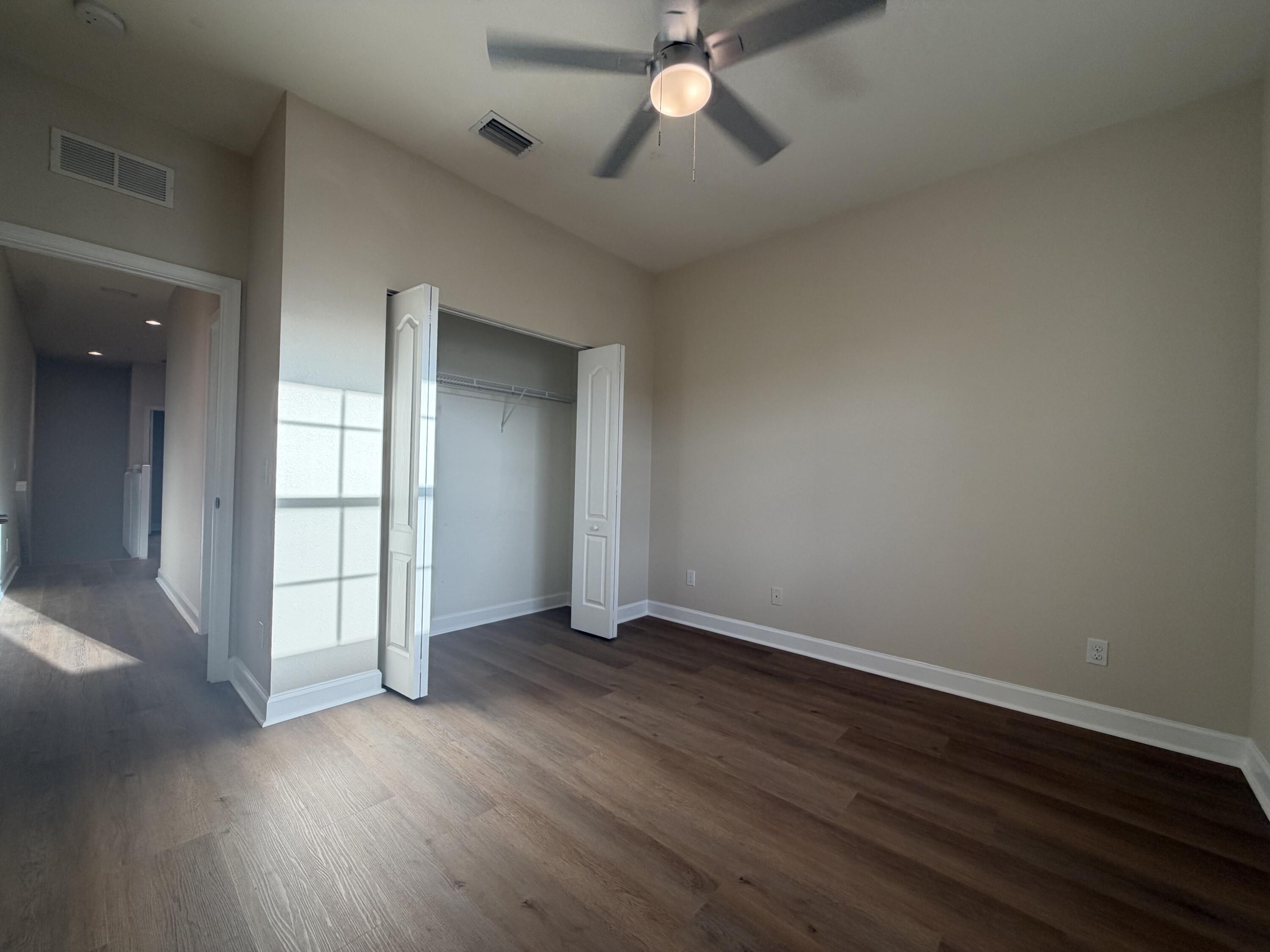 9491 Southwest Merlin Court Stuart, FL 34997 - Photo 18 of 45 a view of an empty room with wooden floor and a window
